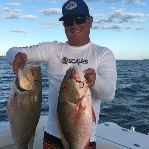 Captain Lacy Ingram holding two mutton snapper aboard his boat