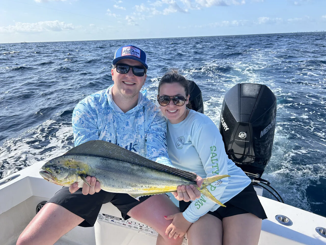 Two anglers holding a bright mahi mahi caught aboard Reel Stubborn Fishing Charters