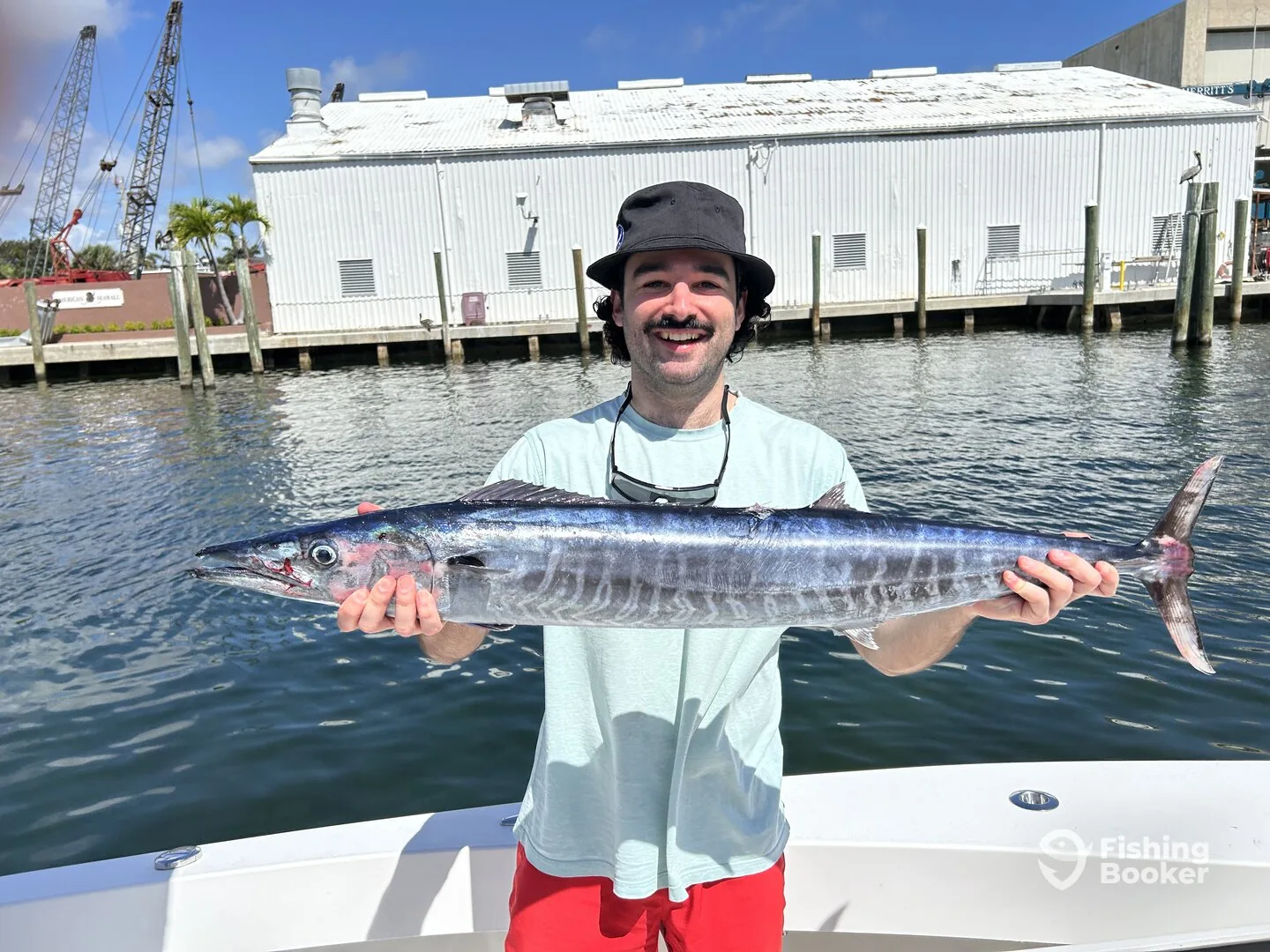 Angler holding a large wahoo caught trolling offshore of Pompano Beach